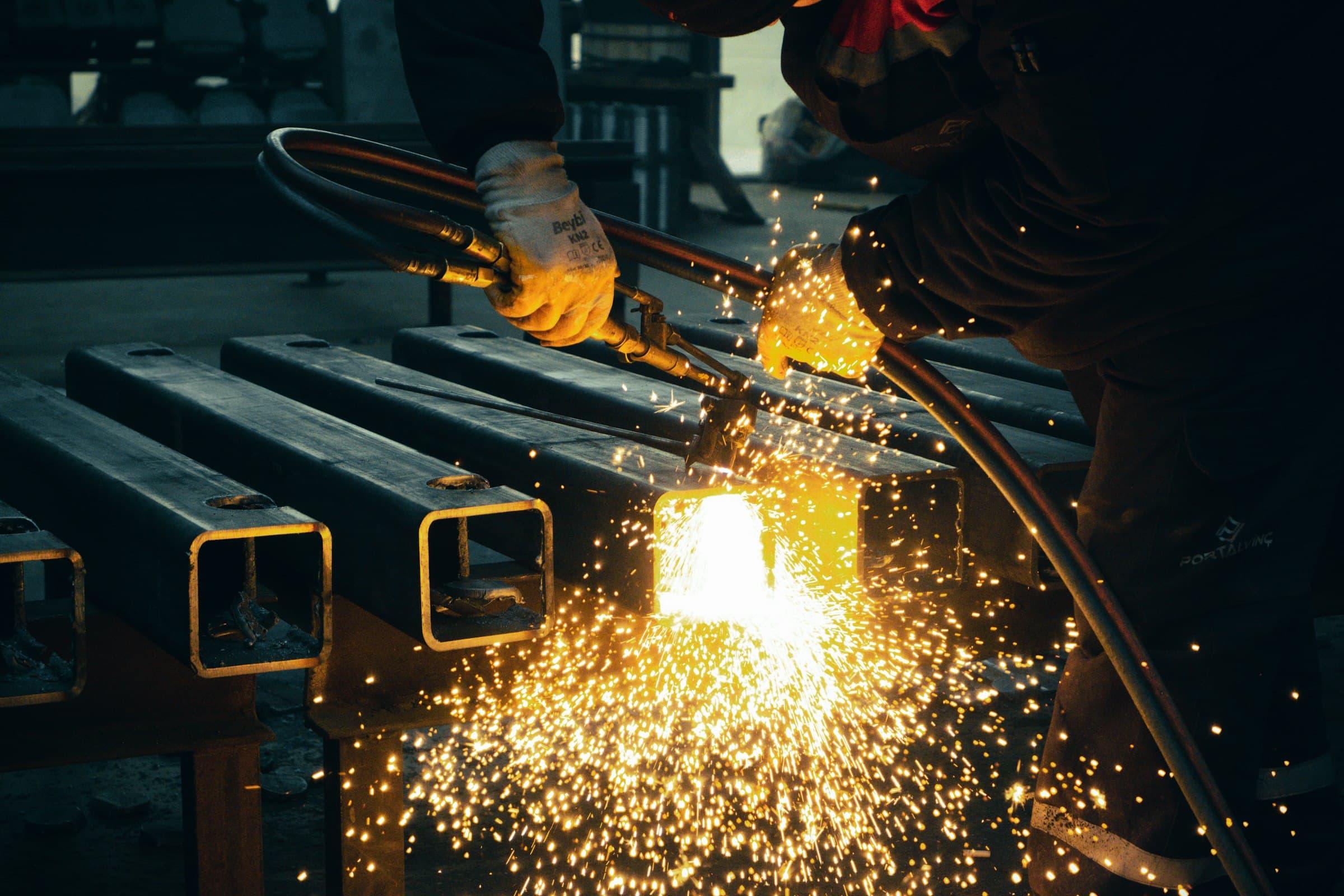 A torch cutting steel, throwing sparks across a fabrication floor